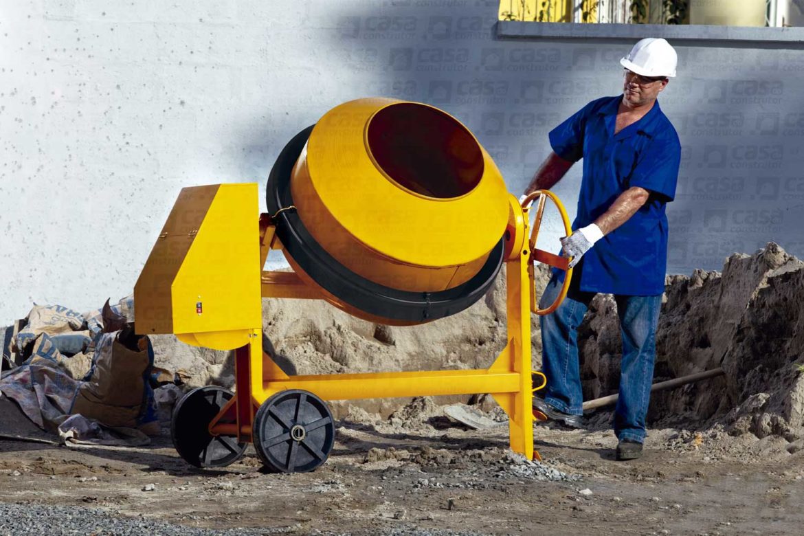 operário de obra manuseando uma máquina de preparar concreto
