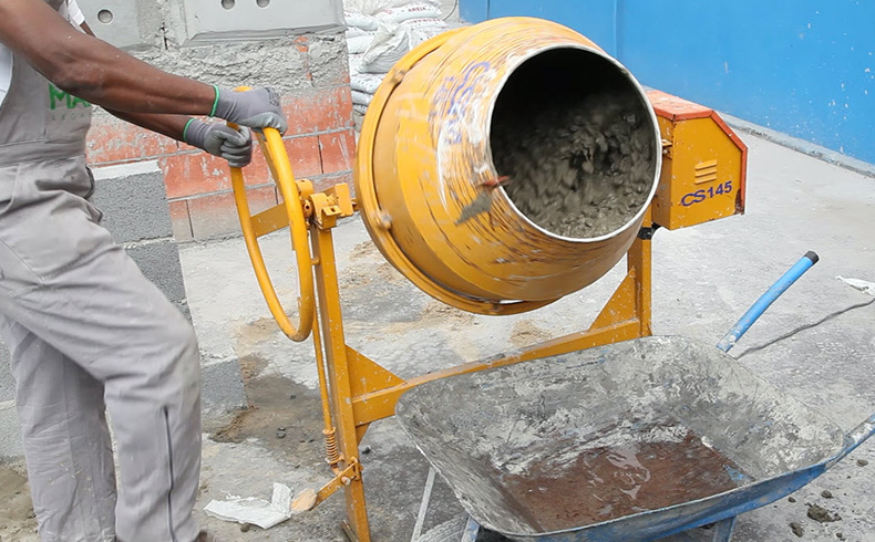 Operário manuseando uma máquina de preparar concreto