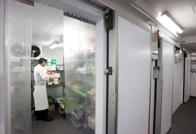 Funcionário dentro de uma câmara frigorífica mantendo alimentos