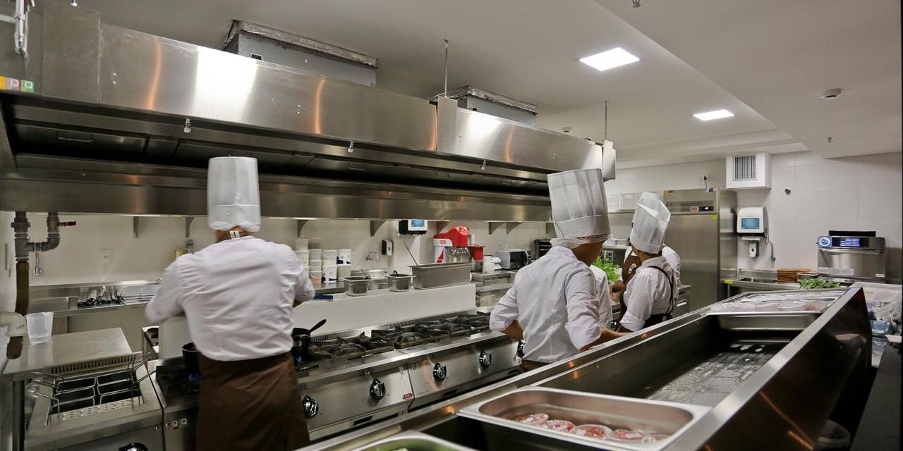 equipe preparando alimentos em cozinha industrial 