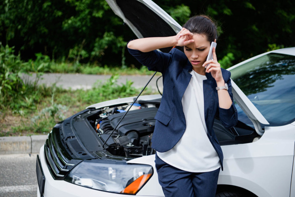 mulher encostada em um carro falando no celular após um acidente