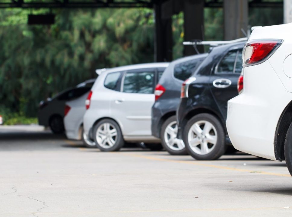 Parte traseira de diversos carros estacionados. 